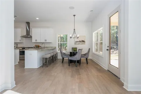 a kitchen with stainless steel appliances granite countertop a refrigerator a sink dishwasher a stove and white cabinets with wooden floor