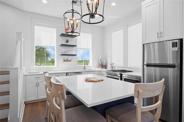 a kitchen with stainless steel appliances a white table chairs and a wooden floors