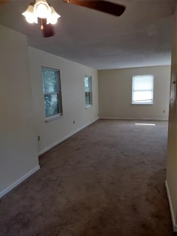 a view of an empty room with a chandelier fan