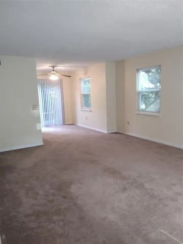a view of a big room with windows and chandelier fan