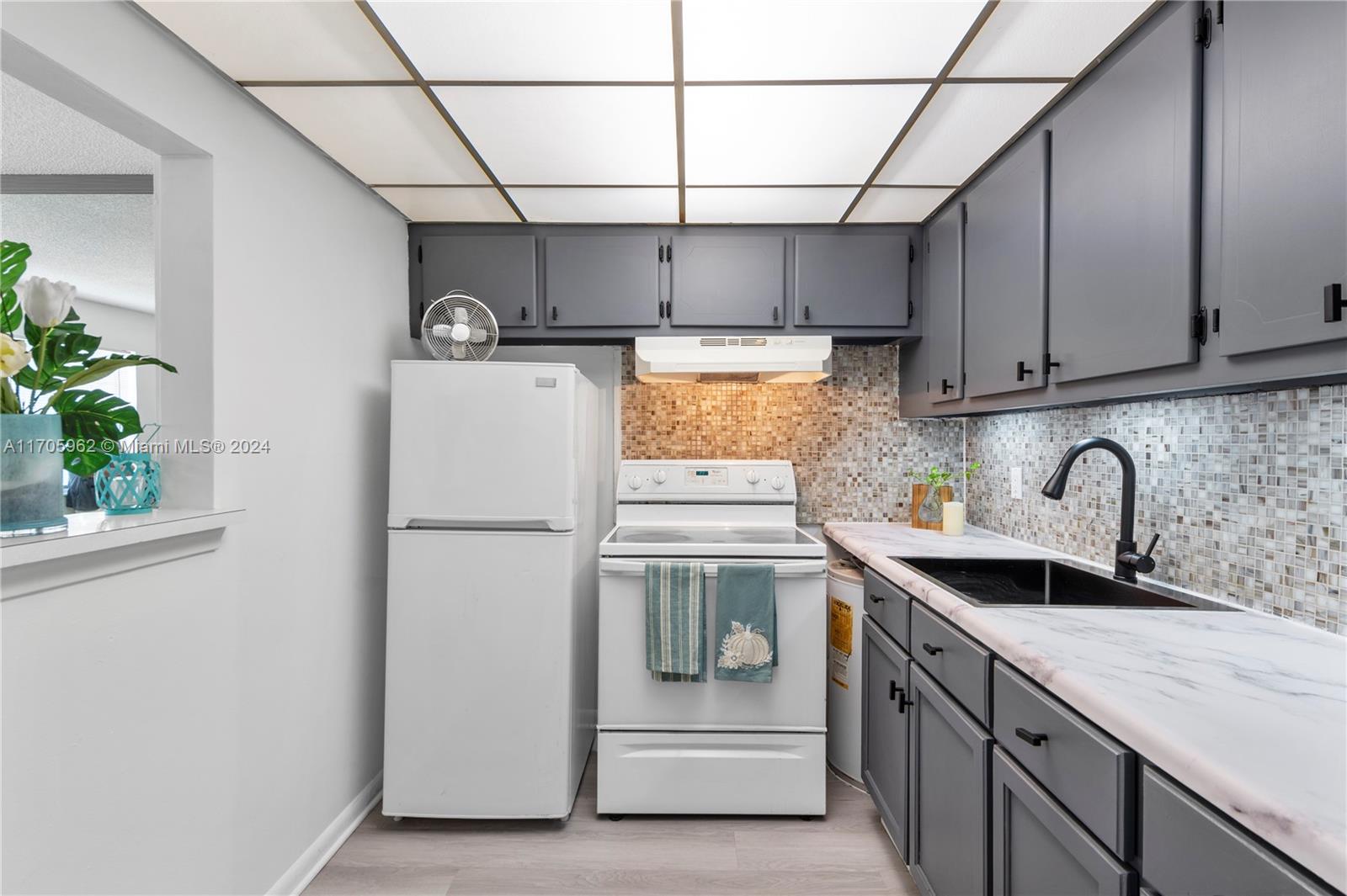 382 Markham R, Unit 382 Deerfield Beach, FL 33442 - Photo 4 of 30 a kitchen with a sink a refrigerator and cabinets