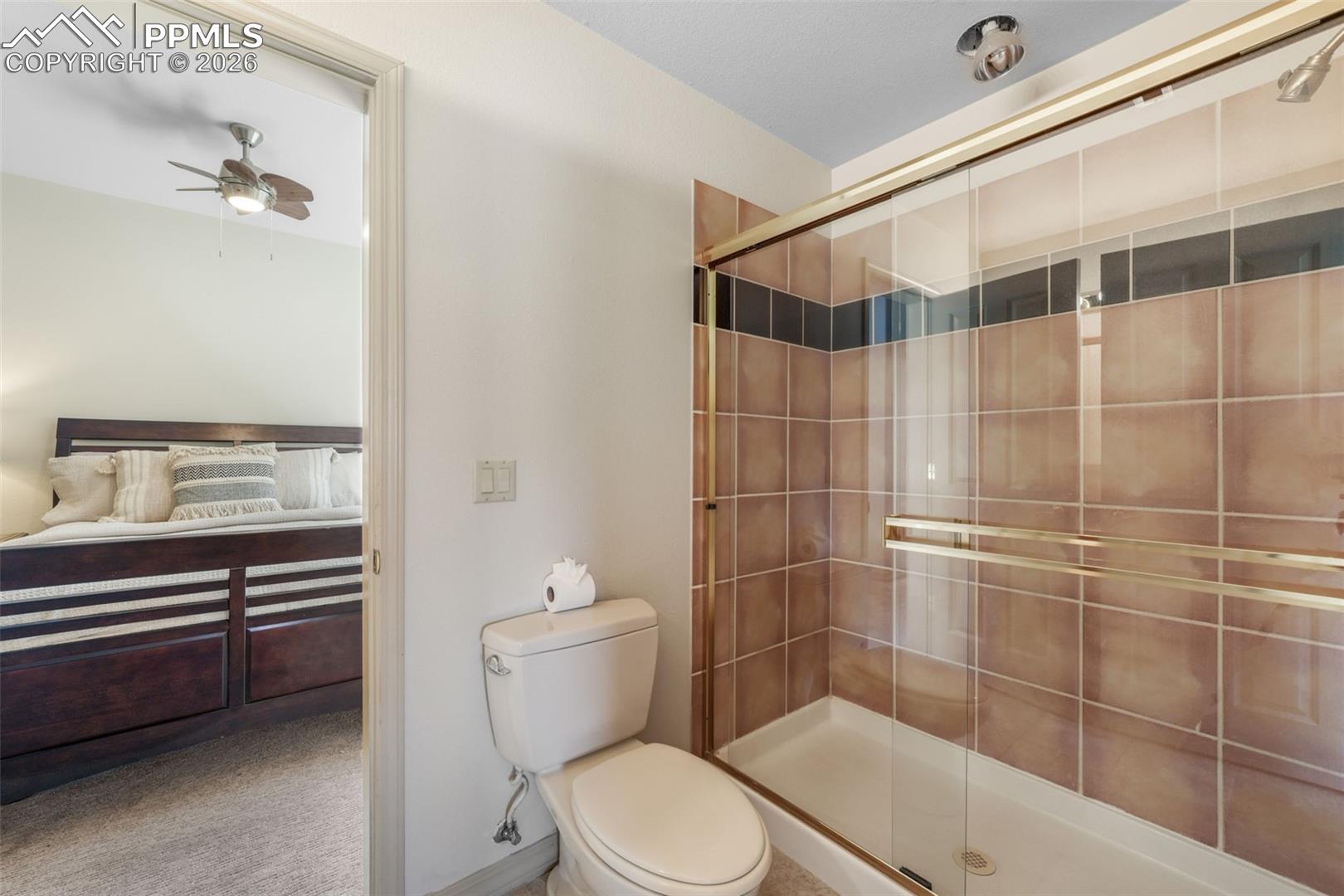 19790 Beacon Lite Road Monument, CO 80132 - Photo 36 of 50 Shower enclosure with tiled walls, gold-finish framing, and a glass sliding door