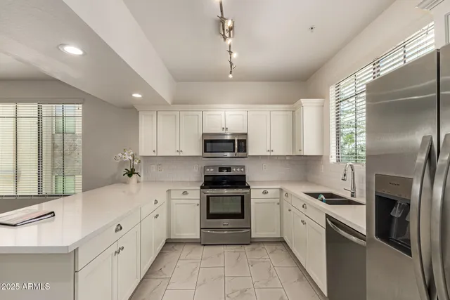 a kitchen with stainless steel appliances granite countertop a stove a sink and a refrigerator