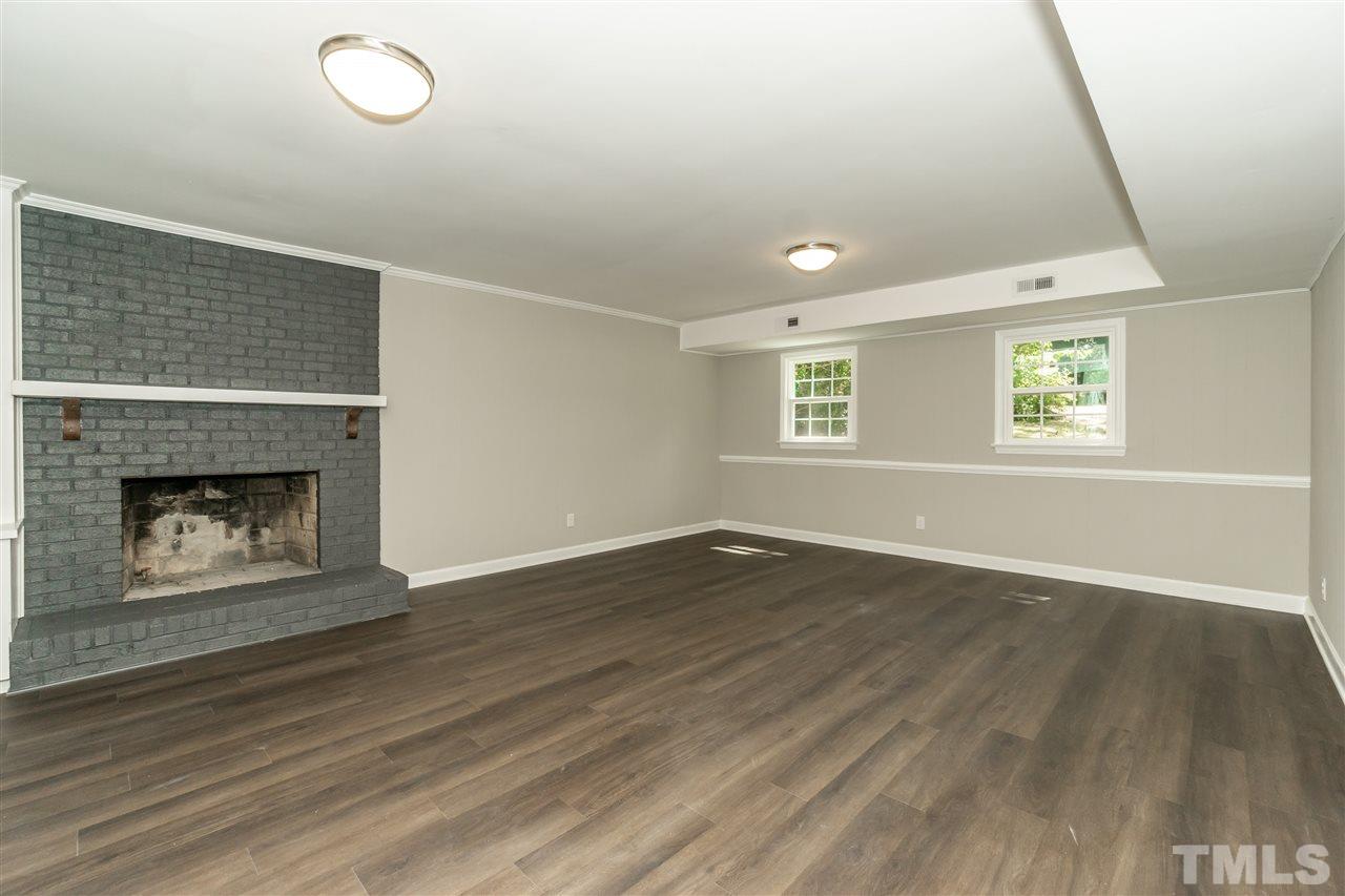 7204 Grist Mill Road Raleigh, NC 27615 - Photo 22 of 30 an empty room with wooden floor fireplace and windows
