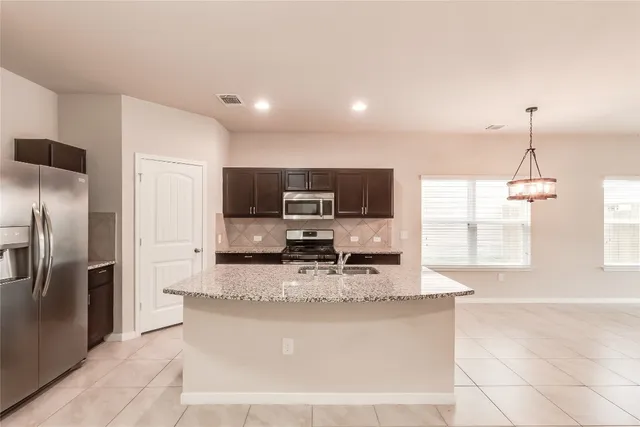 a kitchen with stainless steel appliances granite countertop a sink a stove and a refrigerator