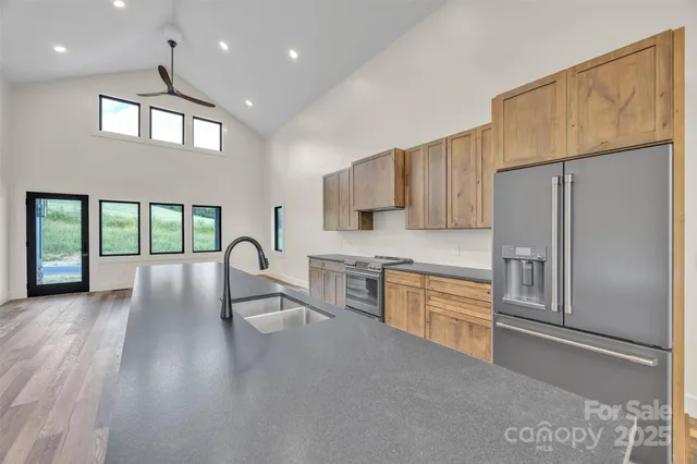 a kitchen with granite countertop a refrigerator a stove top oven a sink and a dining table with wooden floor