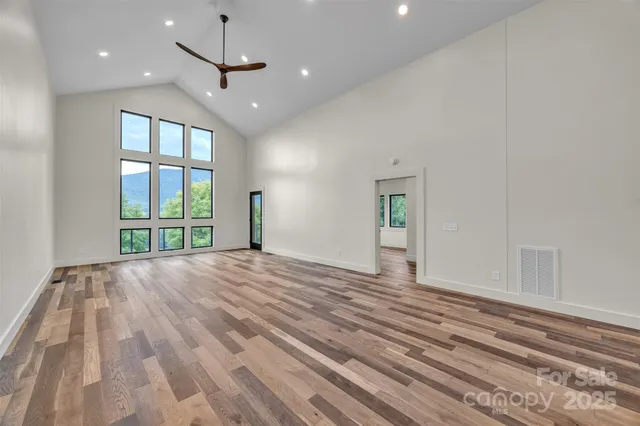 a view of an empty room with a window and wooden floor