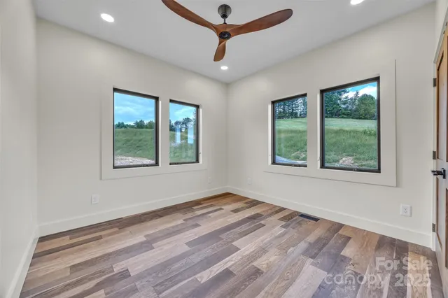 a room with a window a ceiling fan and wooden floor
