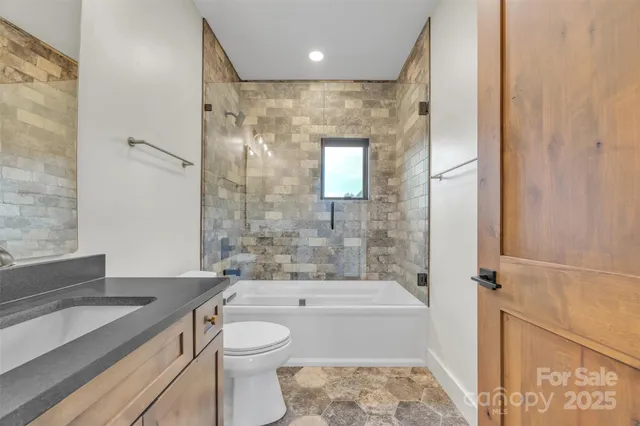 a bathroom with a granite countertop sink a toilet and shower