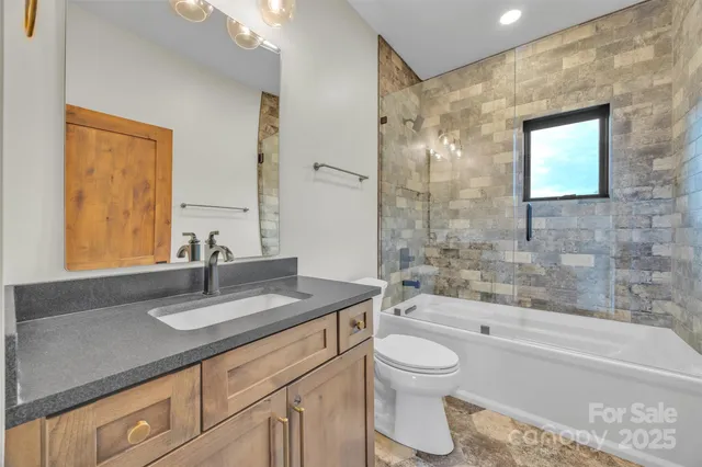 a bathroom with a granite countertop sink a toilet and shower