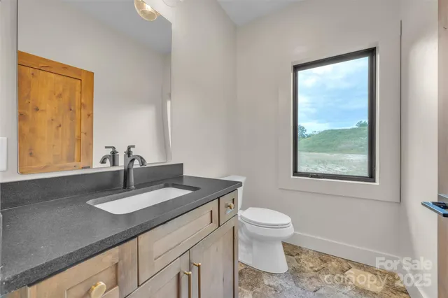 a bathroom with a granite countertop sink a toilet and a window