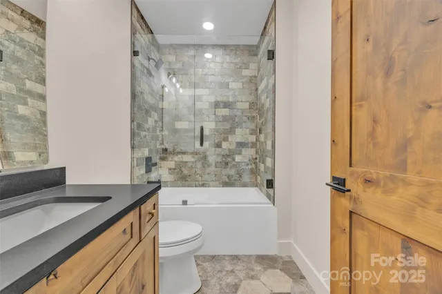 a bathroom with a granite countertop sink a toilet and shower