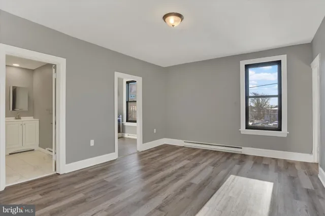 an empty room with wooden floor and windows