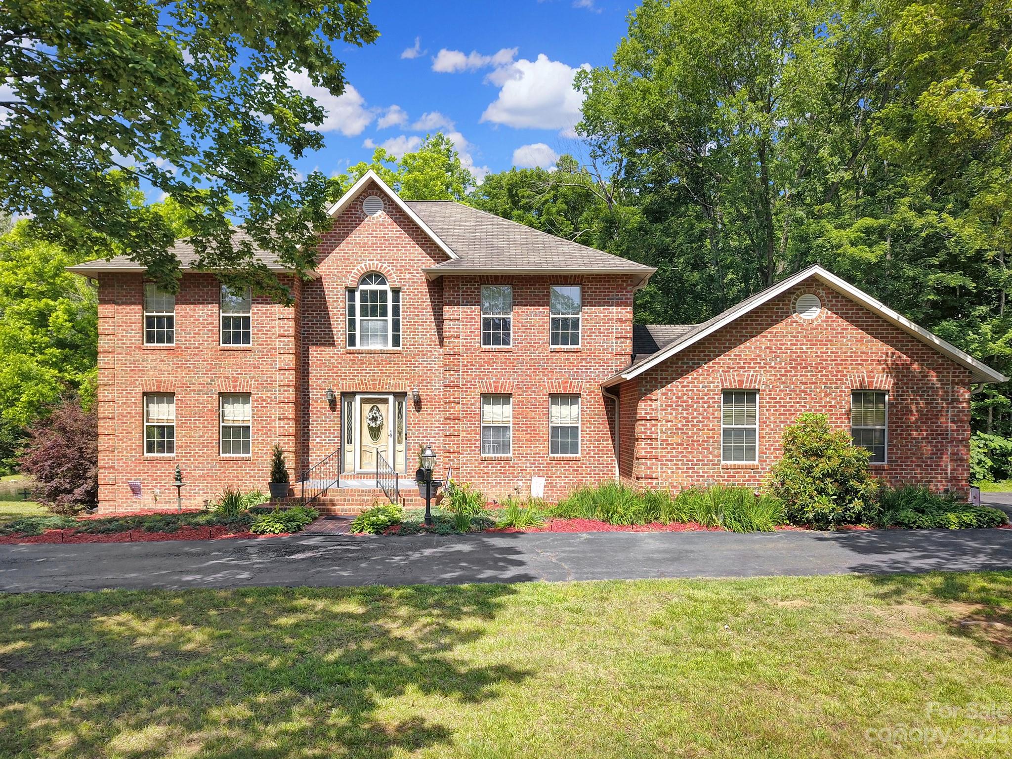 a front view of house with yard and trees in the background