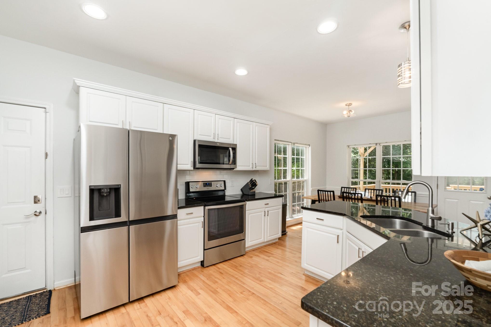11624 Crossroads Place Concord, NC 28025 - Photo 11 of 45 a view of a kitchen with stainless steel appliances granite countertop a stove a sink dishwasher a refrigerator and a microwave oven with wooden floor