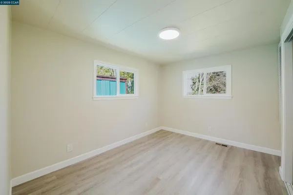 an empty room with a painting and a window