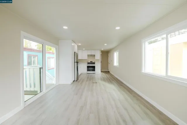 a view of empty room with kitchen and window