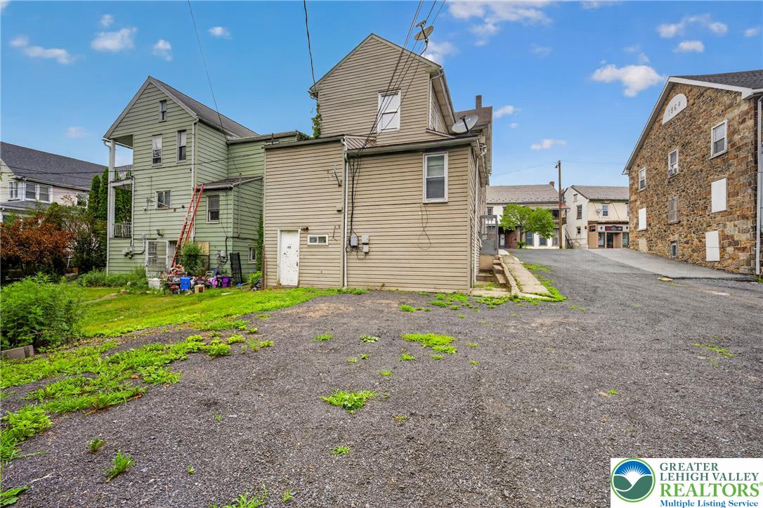 313 Main Street Slatington, PA 18080 - Photo 64 of 73 A gravel parking area leads to the rear of a multi-story residence with a small grassy yard.
