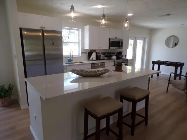 a kitchen with stainless steel appliances granite countertop a table chairs sink refrigerator and microwave