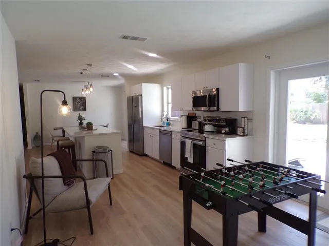 a kitchen with stainless steel appliances a stove a sink dishwasher a refrigerator and a microwave oven with wooden floor