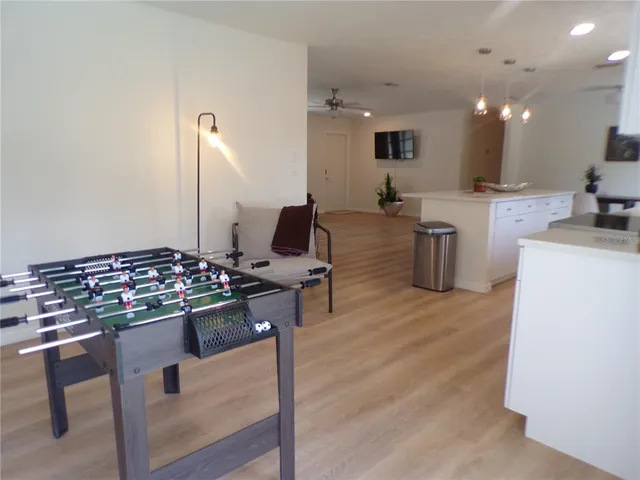 a view of a kitchen with kitchen island a stove a sink dishwasher a dining table and chairs with wooden floor