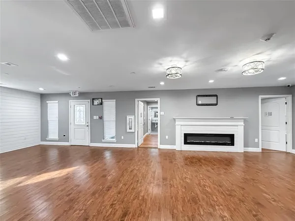 an empty room with wooden floor fireplace and windows