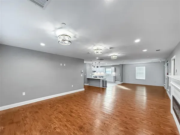 a view of an empty room with kitchen and window