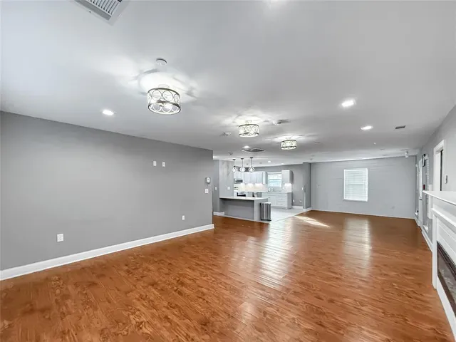 a view of an empty room with kitchen and window