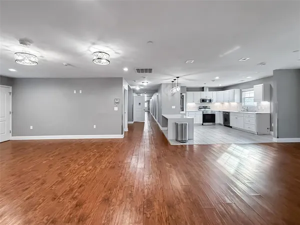a view of a big room with wooden floor and a kitchen