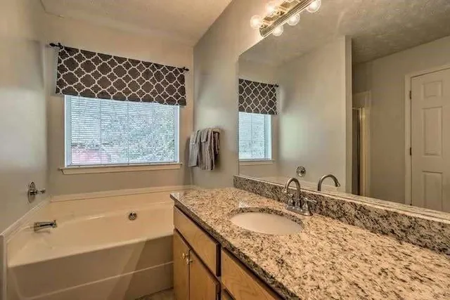 a bathroom with a granite countertop sink mirror and a bathtub
