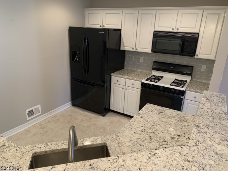 13 Potomac Drive, Unit 13 Bernards, NJ 07920 - Photo 2 of 16 a kitchen with granite countertop a refrigerator stove and microwave