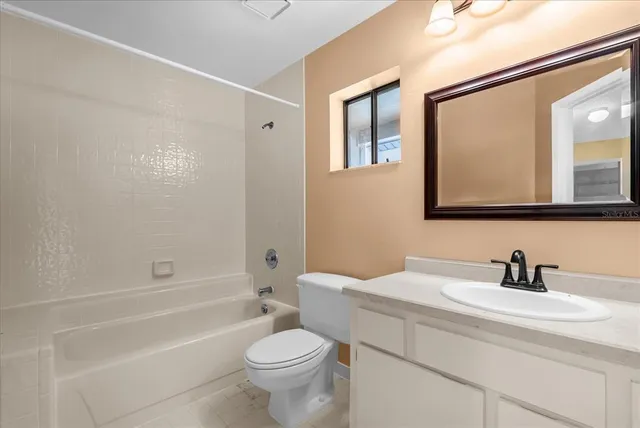 a bathroom with a toilet a sink a mirror a bathtub and vanity