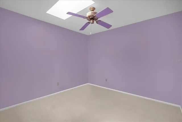 an empty room with a ceiling fan and carpet