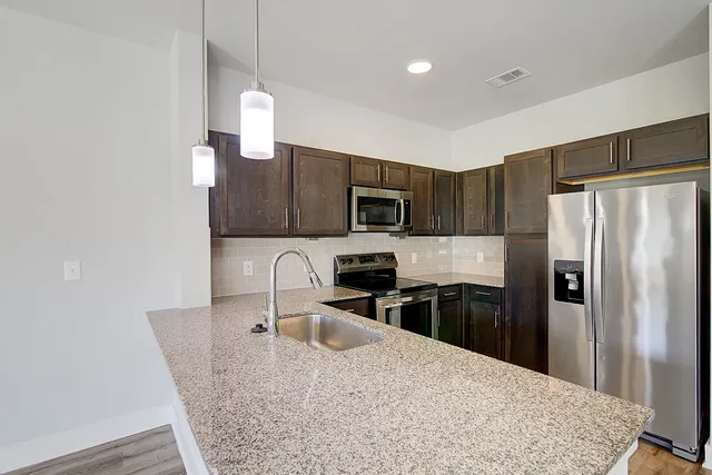 a kitchen with stainless steel appliances granite countertop a refrigerator a stove a sink a microwave and island