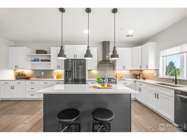 a kitchen with stainless steel appliances granite countertop a sink a stove a refrigerator and white cabinets