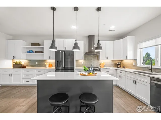 a kitchen with stainless steel appliances granite countertop a sink a stove a refrigerator and white cabinets