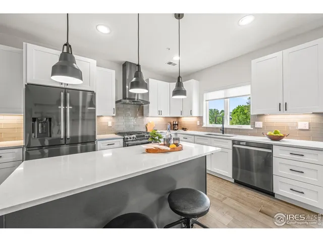 a kitchen with stainless steel appliances kitchen island granite countertop a sink a stove and a wooden floors