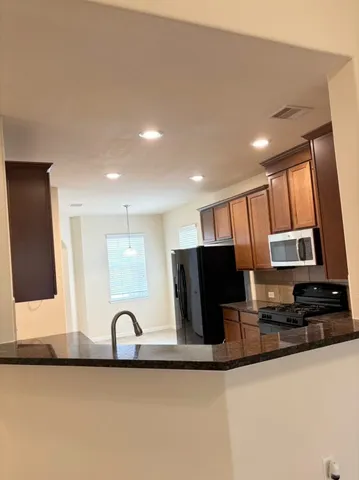 a kitchen with stainless steel appliances granite countertop a refrigerator a stove a sink and a microwave