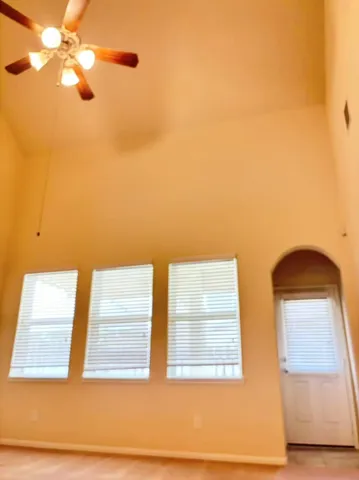 an empty room with a chandelier fan and windows