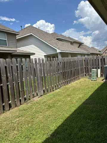 a view of a yard with flower plants and wooden fence