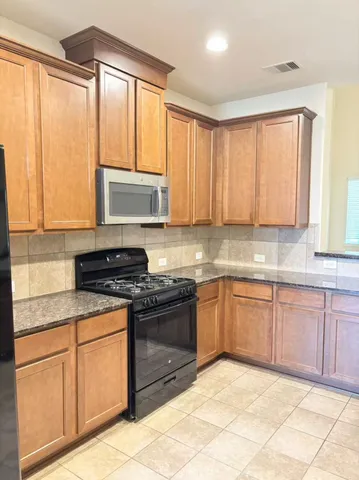 a kitchen with stainless steel appliances granite countertop a stove a sink and a microwave