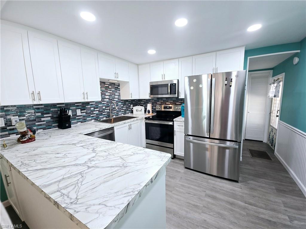 19 Moorhead Manor Naples, FL 34112 - Photo 5 of 33 a kitchen with granite countertop a refrigerator a sink a stove top oven a cabinetry and kitchen island