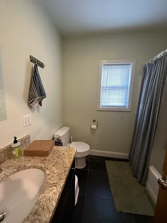 a bathroom with a granite countertop sink a toilet and mirror