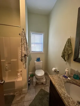 a bathroom with a granite countertop sink toilet and shower