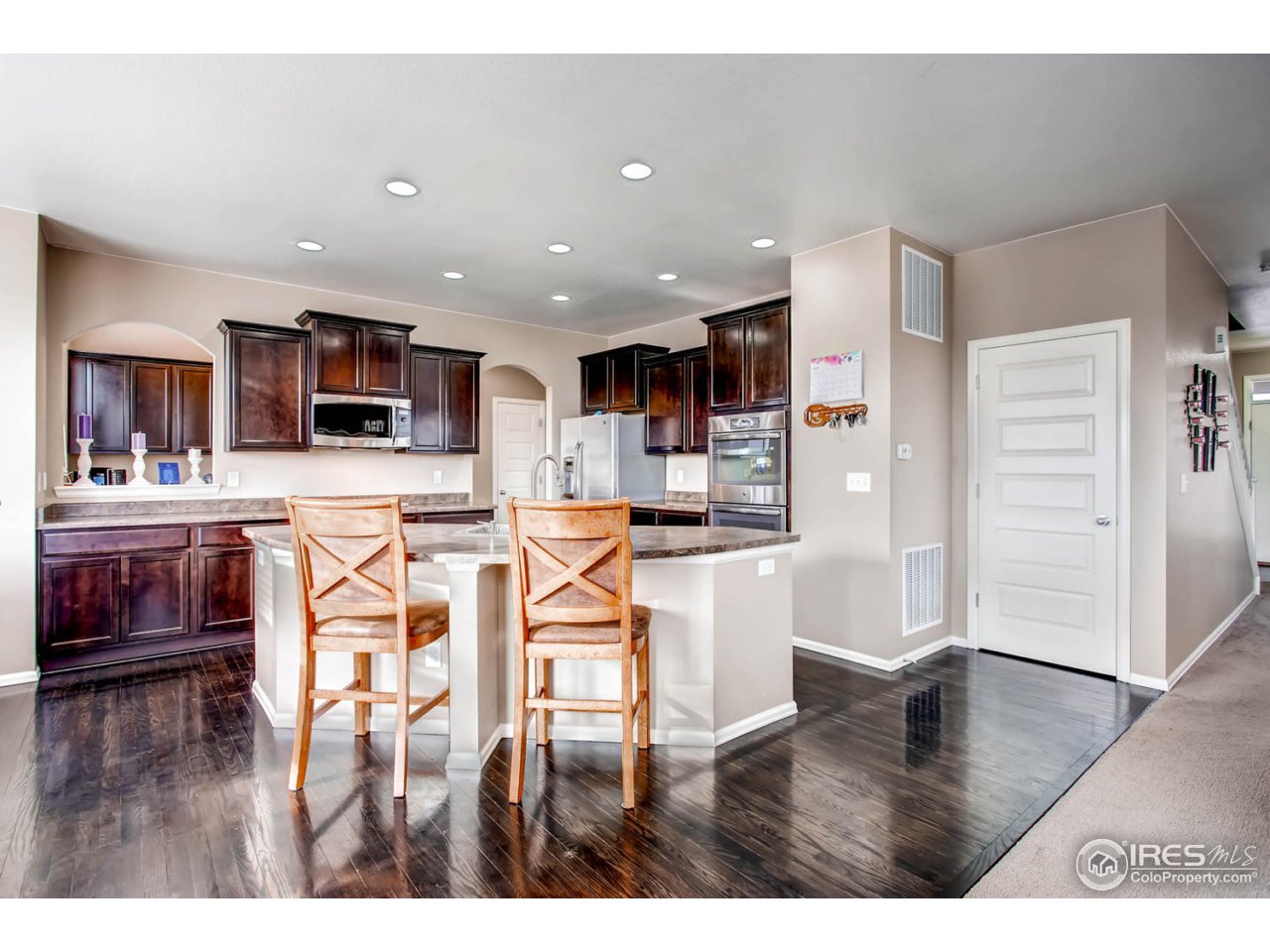 8615 Raspberry Drive Frederick, CO 80504 - Photo 11 of 28 a kitchen with stainless steel appliances kitchen island granite countertop a refrigerator and a stove top oven