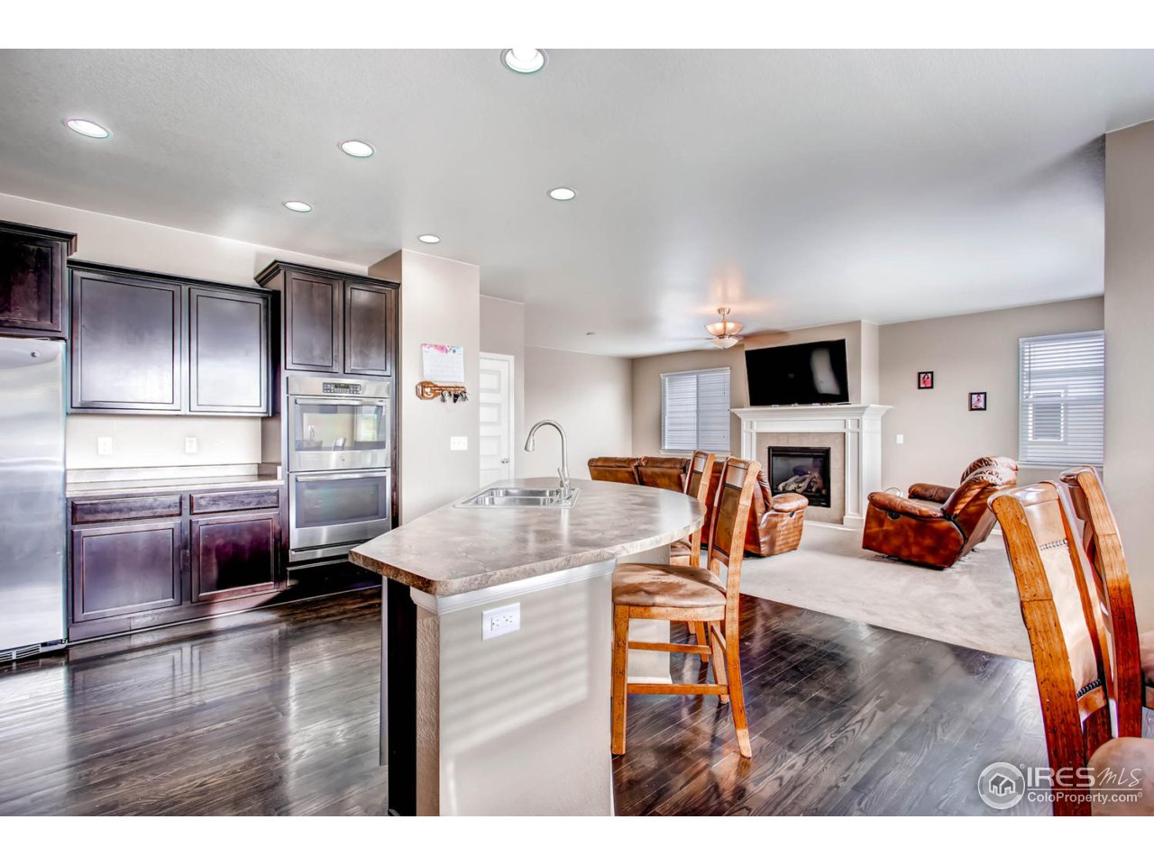 8615 Raspberry Drive Frederick, CO 80504 - Photo 12 of 28 a kitchen with stainless steel appliances kitchen island granite countertop a refrigerator a stove and a sink with wooden floor