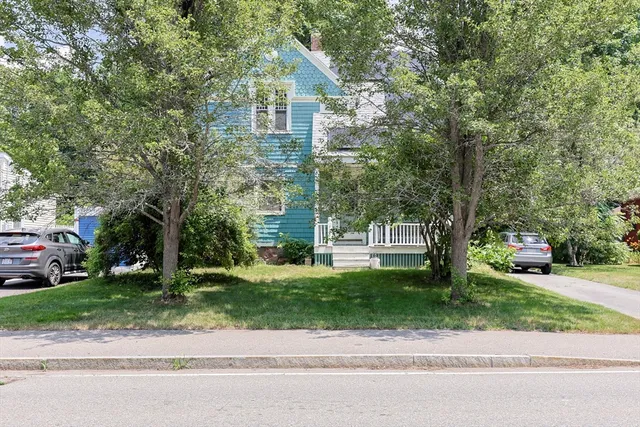 a front view of a house with a garden and trees