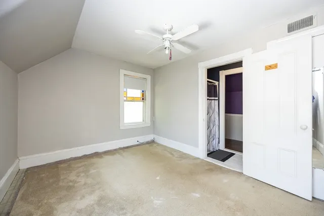 an empty room with a ceiling fan and window