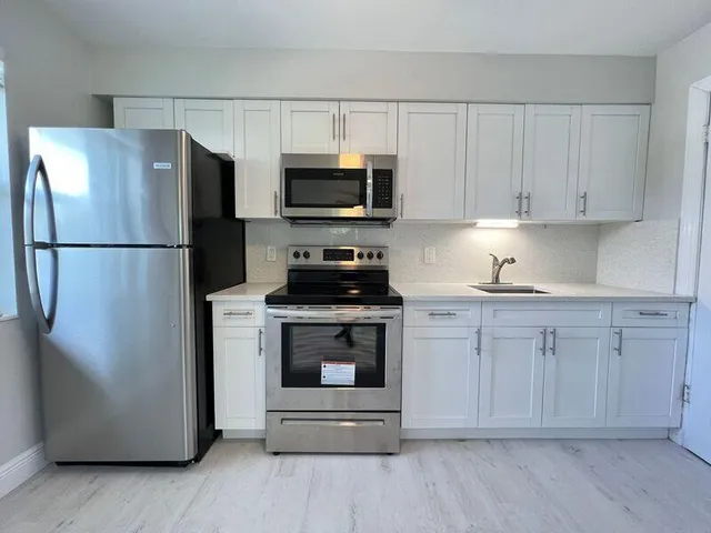 a kitchen with white cabinets and stainless steel appliances