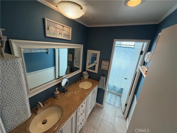 a bathroom with a granite countertop double vanity sink and mirror